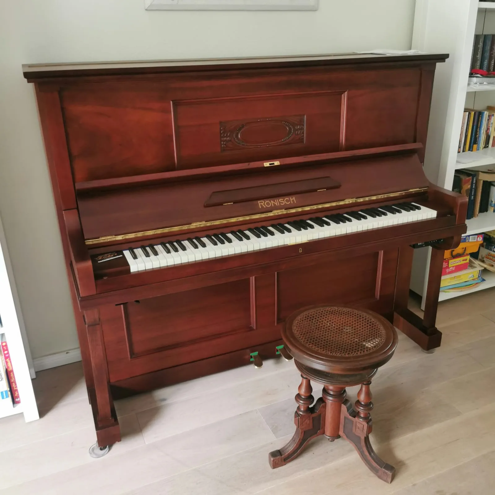 Braunes Rönisch-Klavier mit antikem Drehhocker im Wohnzimmer